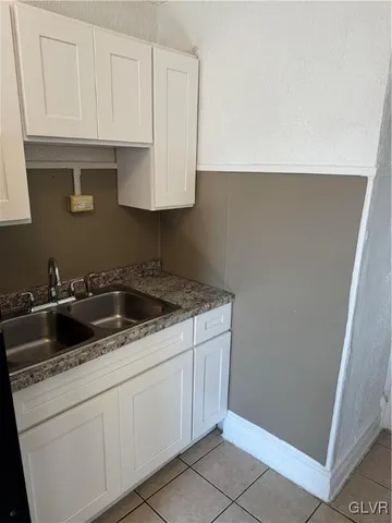 a kitchen with a refrigerator and white cabinets