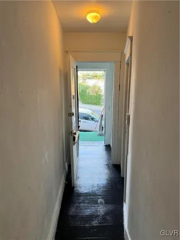 a view of a hallway with wooden floor and a bathroom