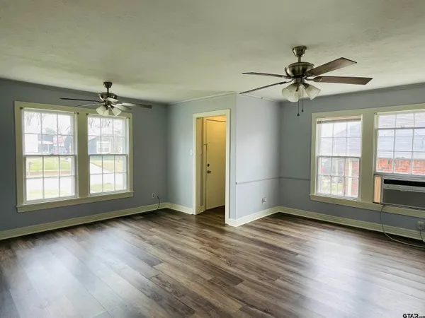 a view of an empty room with wooden floor and a window