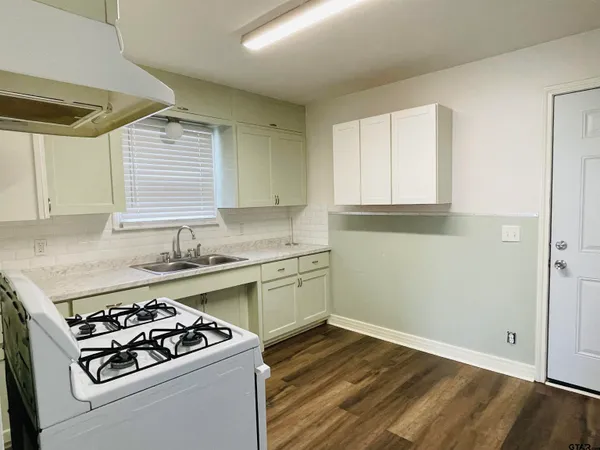 a kitchen with a stove a sink and wooden floor