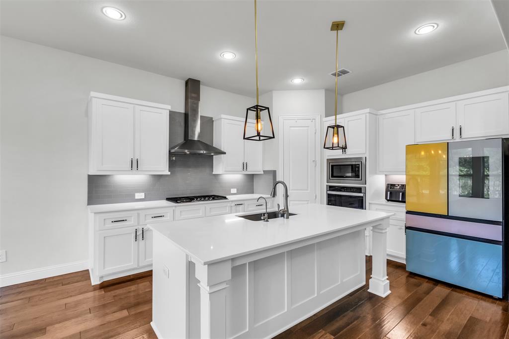 3511 Solaro Lane Rockwall, TX 75087 - Photo 12 of 40 a kitchen with stainless steel appliances a sink stove and wooden floor