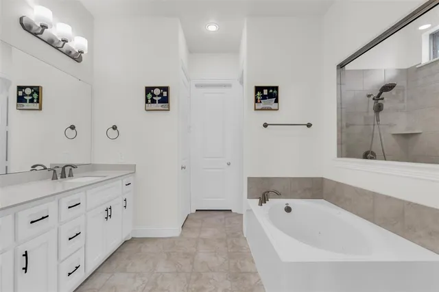 a bathroom with a tub a sink and mirror