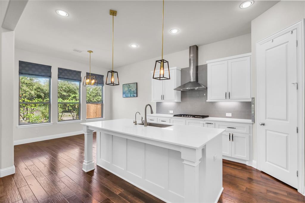 3511 Solaro Lane Rockwall, TX 75087 - Photo 2 of 40 a kitchen with a stove a sink a center island and wooden floor