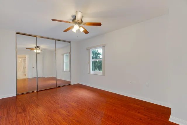 a view of an empty room with window and wooden floor
