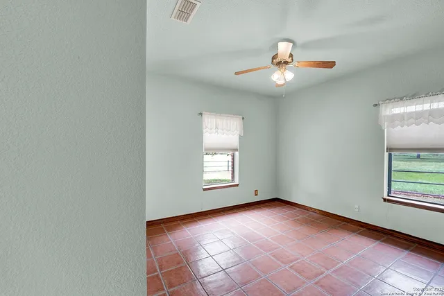 an empty room with windows and ceiling fan