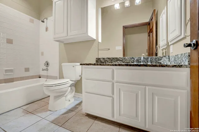 a bathroom with a granite countertop toilet a sink and a bathtub