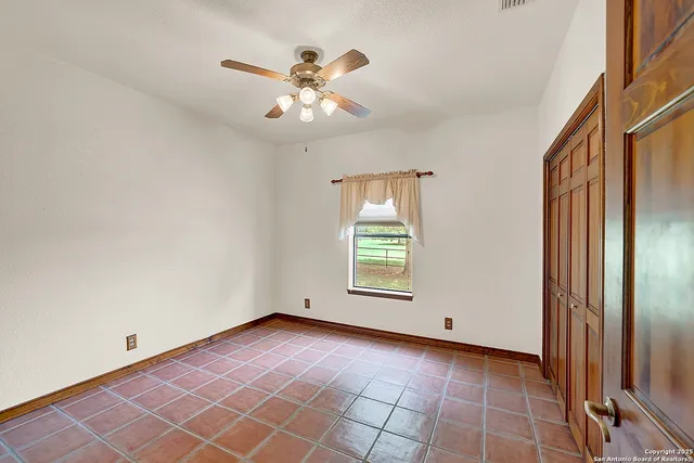 an empty room with windows and chandelier fan