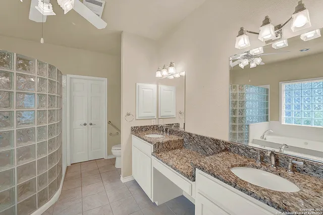 a bathroom with a granite countertop double vanity sink a mirror and a shower