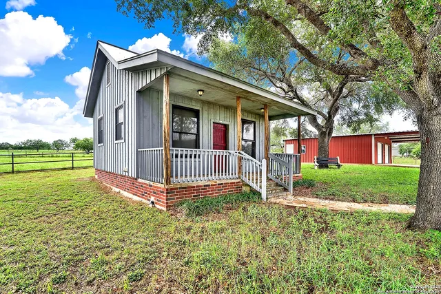 a view of a house with a yard and large tree