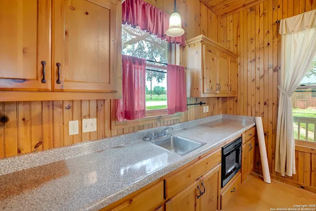 a kitchen with stainless steel appliances granite countertop a sink a oven and a dining table with wooden cabinet