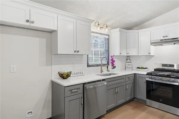 a kitchen with stainless steel appliances granite countertop a sink dishwasher a stove and cabinets with wooden floor