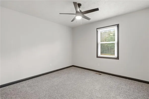 an empty room with a window and a fan