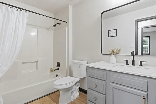 a bathroom with a toilet a sink a mirror a shower and vanity