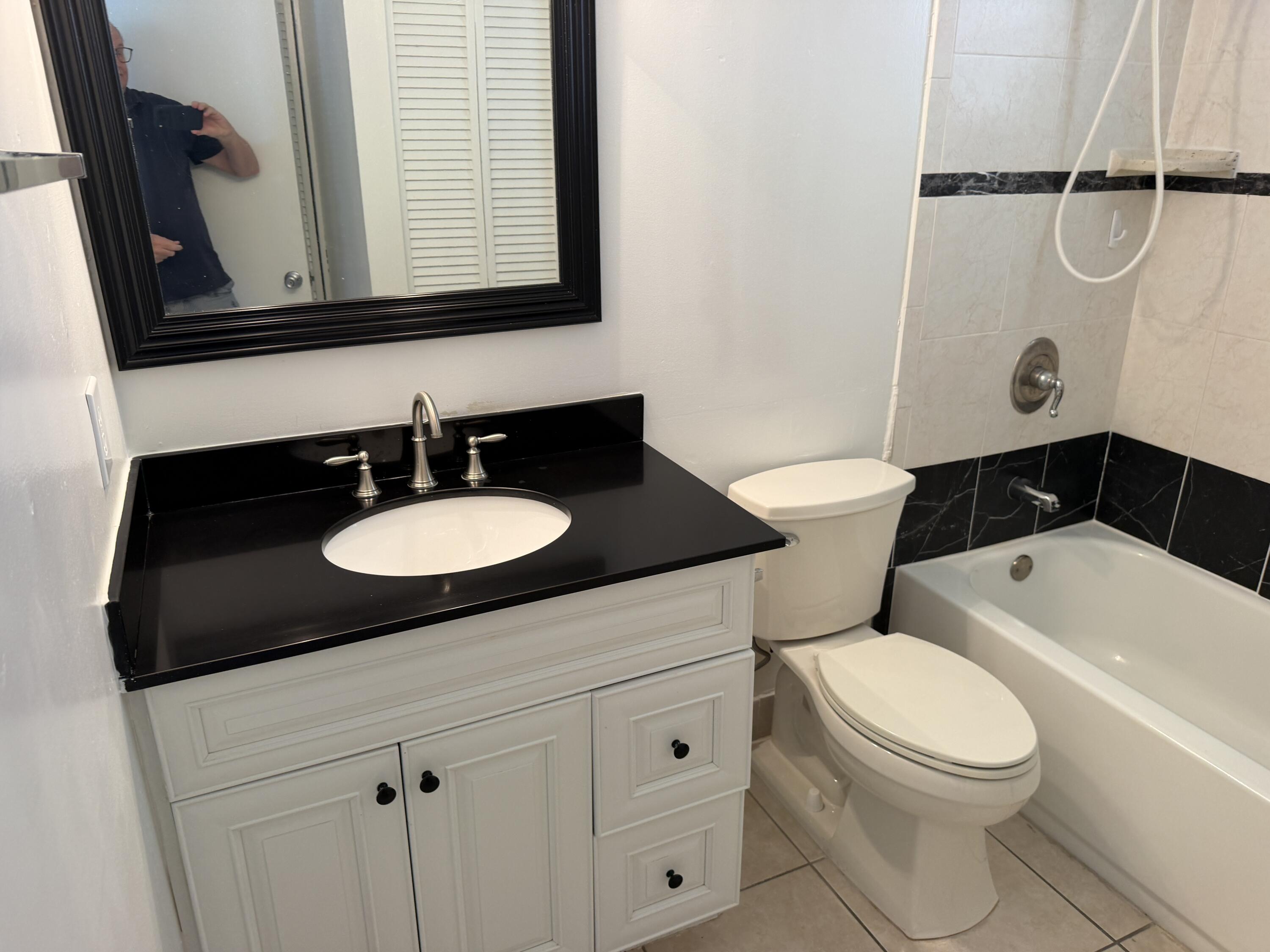 506 Davis Road, Unit 70 Palm Springs, FL 33461 - Photo 25 of 25 a bathroom with a granite countertop sink toilet and mirror