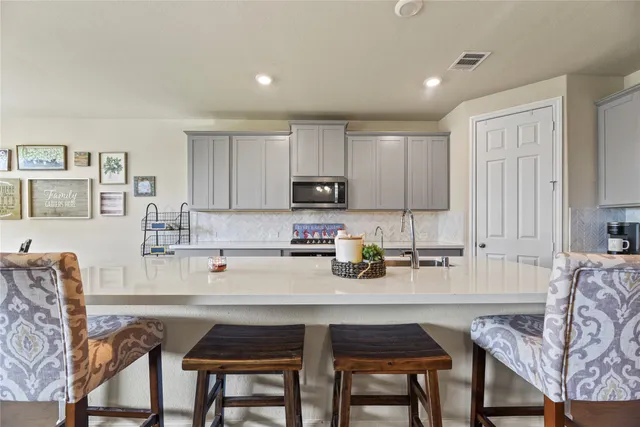 a kitchen with stainless steel appliances a table and chairs in it