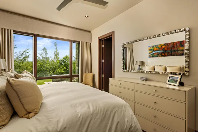 a spacious bedroom with a large bed and a flat tv screen on dresser