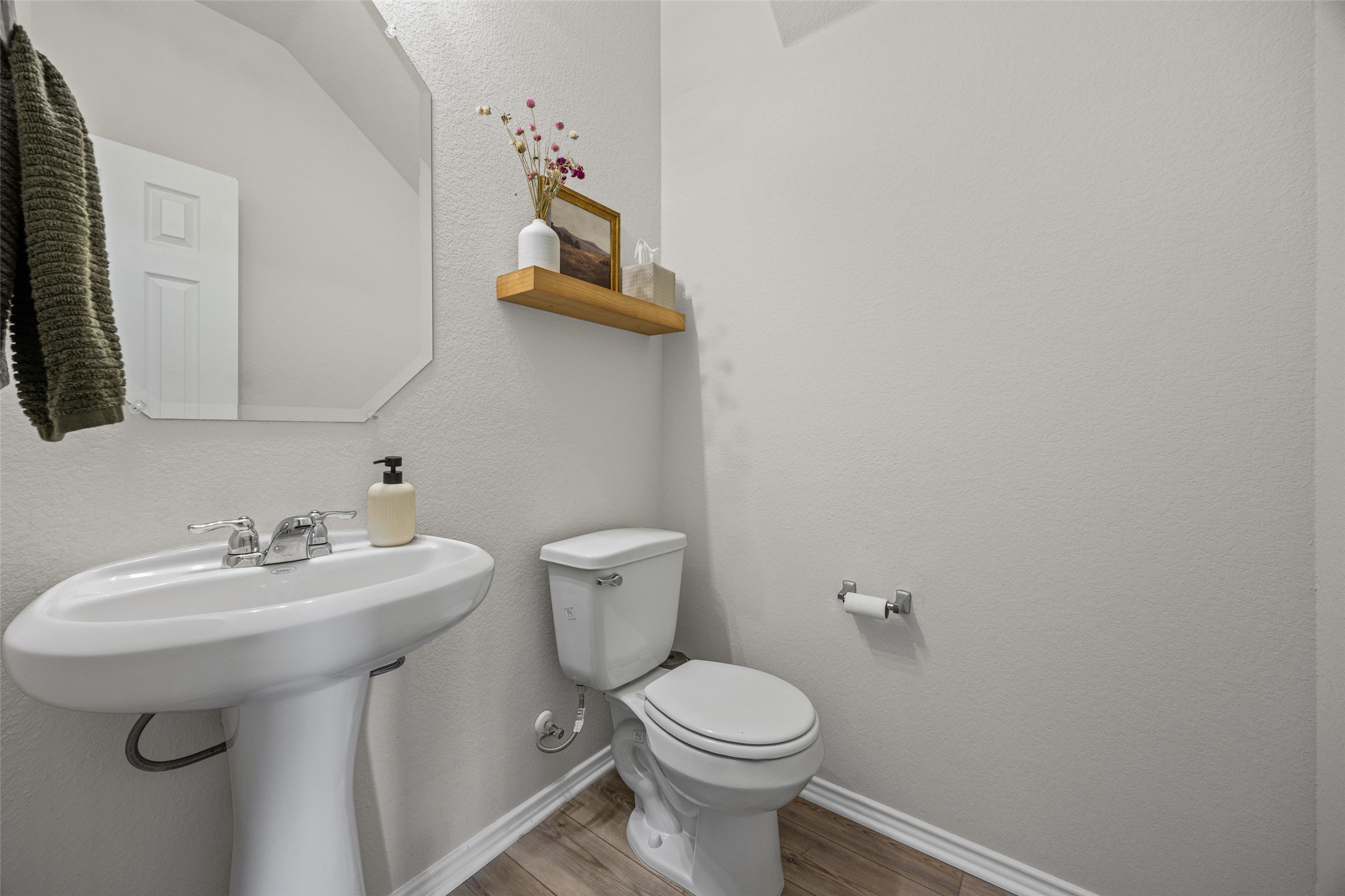208 Orange Road Buda, TX 78610 - Photo 10 of 31 A compact powder room with pedestal sink, mirror, and a wall-mounted shelf, perfect for guests.