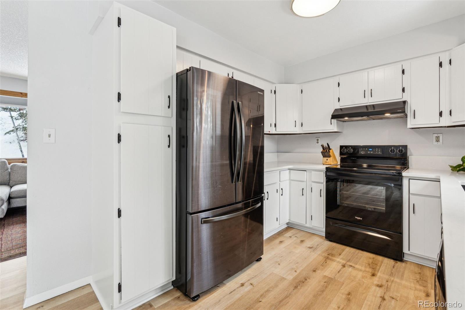 28254 Tresine Drive Evergreen, CO 80439 - Photo 12 of 44 a kitchen with a refrigerator stove and white cabinets