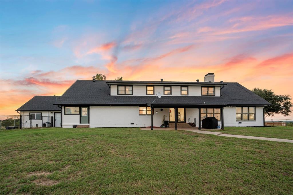 10902 Clear Creek Road West Sanger, TX 76266 - Photo 21 of 40 Back of house at dusk with a chimney, a lawn, a shingled roof, and brick siding