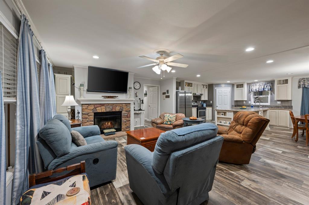 10902 Clear Creek Road West Sanger, TX 76266 - Photo 28 of 40 2nd House Living room with wood finished floors, recessed lighting, ceiling fan, a stone fireplace, and ornamental molding