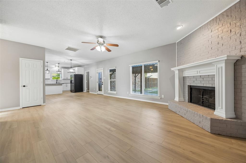 753 Summerfield Drive Allen, TX 75002 - Photo 11 of 40 Spacious room featuring wood-finish flooring, a brick fireplace with a white mantel, and a ceiling fan