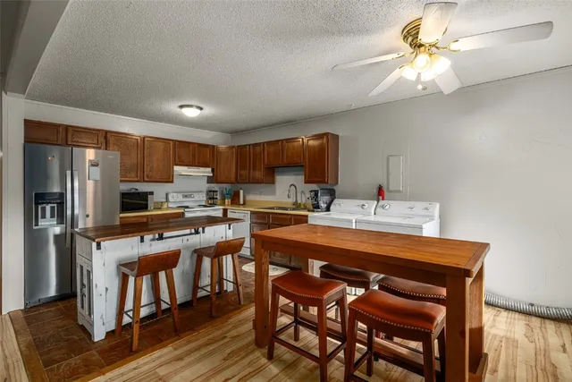 a kitchen with stainless steel appliances a sink a stove a refrigerator cabinets and a dining table