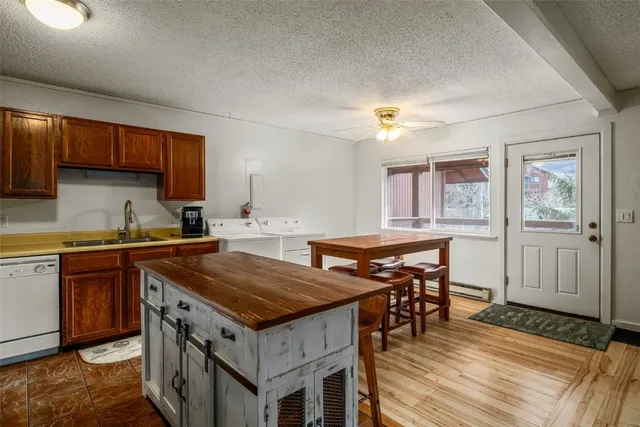 a kitchen with a stove a sink dishwasher and a refrigerator with wooden floor