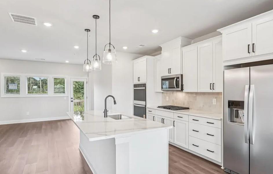 6060 Molo Lane Cumming, GA 30041 - Photo 3 of 14 a kitchen with stainless steel appliances kitchen island granite countertop a refrigerator a sink dishwasher a stove and white cabinets with wooden floor