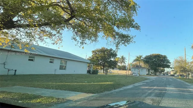 a view of a white house with a yard and plants