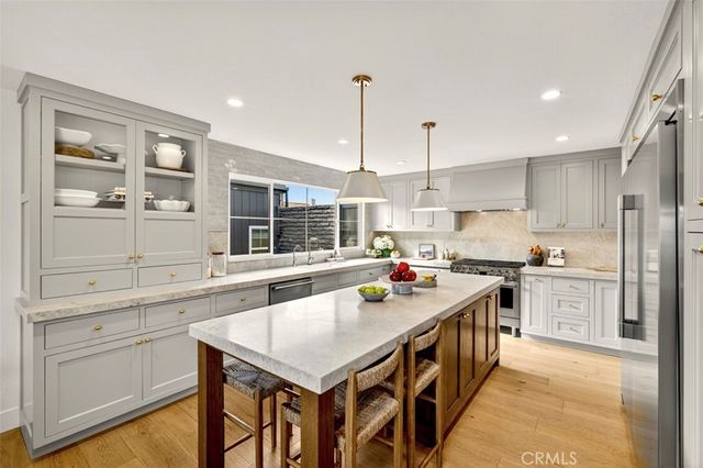 a kitchen with a stove a sink a kitchen island with chairs and wooden cabinets