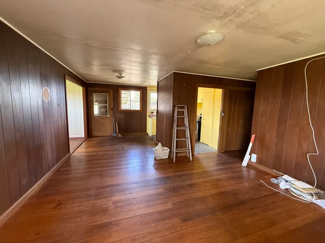 an empty room with wooden floor chandelier and windows