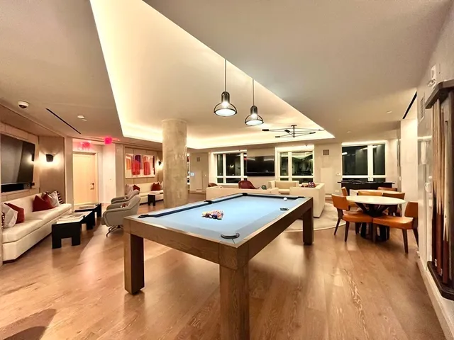 a living room with furniture pool table and flat screen tv