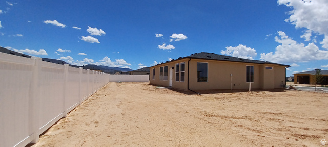 4956 North 925 East, Unit 87 Enoch, UT 84721 - Photo 16 of 19 Expansive backyard featuring a new perimeter fence, stucco exterior, multiple window placements, and a new shingle roof