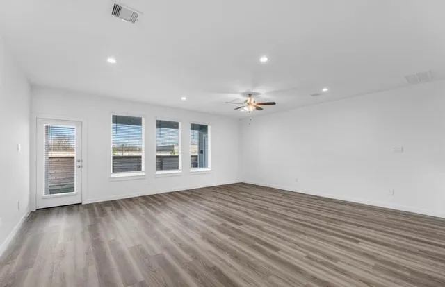 a view of an empty room with wooden floor and a window