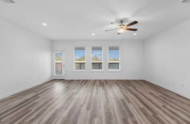 a view of an empty room with a window and wooden floor