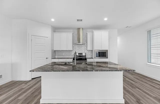 a kitchen with kitchen island granite countertop a sink cabinets and window