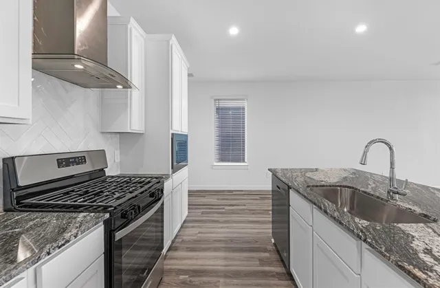 a kitchen with granite countertop a sink stainless steel appliances and cabinets