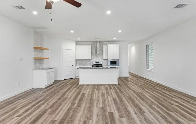 a large white kitchen with kitchen island a sink dishwasher a stove and a refrigerator with wooden floor