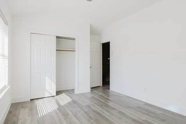 an empty room with wooden floor and windows