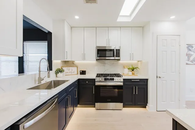 a kitchen with stainless steel appliances granite countertop a stove top oven a sink dishwasher and a refrigerator with wooden cabinets