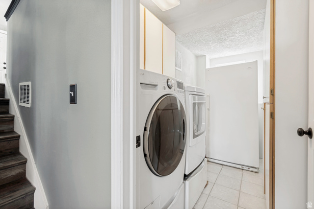 332 East Magellan Lane Elk Ridge, UT 84651 - Photo 16 of 24 Dedicated laundry area featuring a front-load washer and dryer set, overhead cabinetry, and tiled flooring