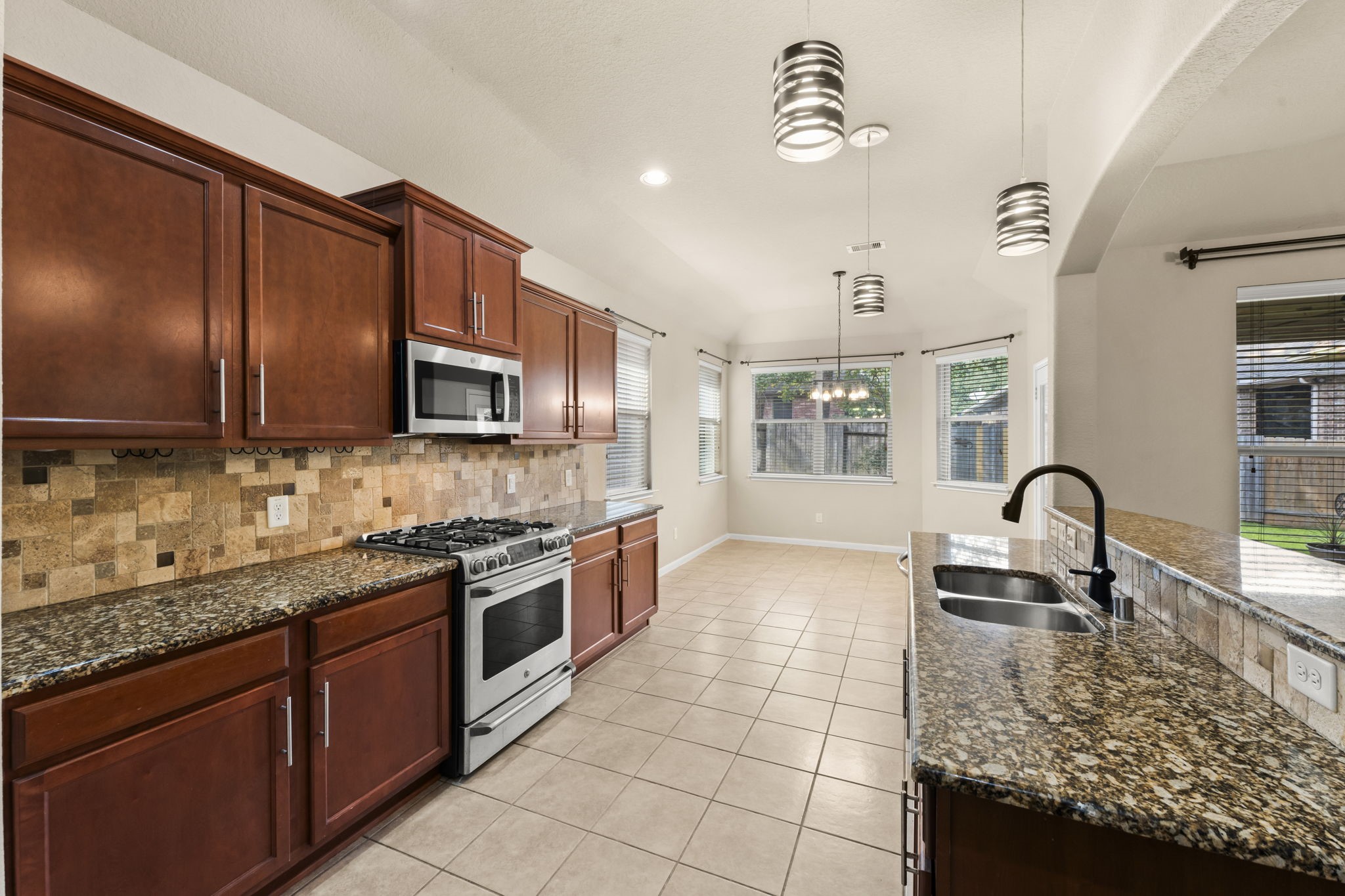 1906 Pagemill Lane Conroe, TX 77304 - Photo 15 of 41 a kitchen with kitchen island granite countertop a stove a sink and a microwave