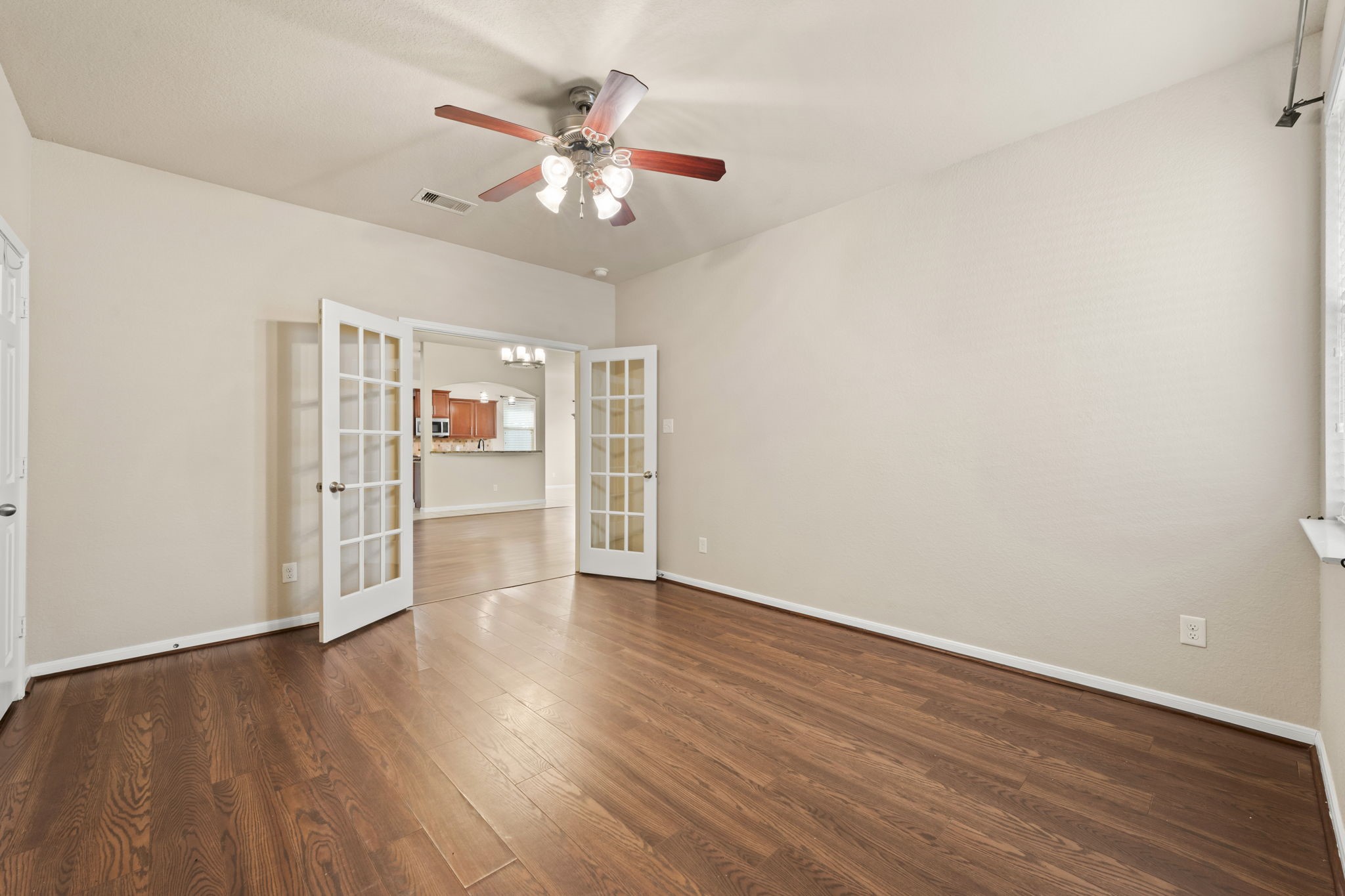1906 Pagemill Lane Conroe, TX 77304 - Photo 21 of 41 an empty room with wooden floor chandelier fan and windows