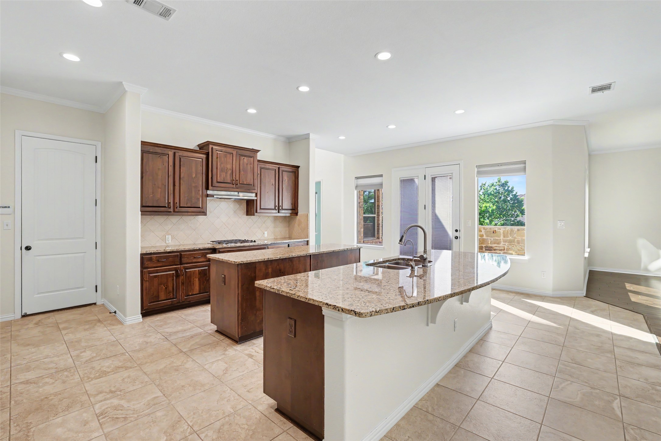 1020 Winding Way Drive Georgetown, TX 78628 - Photo 10 of 32 Kitchen featuring tasteful backsplash, light stone countertops, recessed lighting, ornamental molding, and light tile patterned flooring