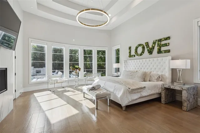 a spacious bedroom with a bed a mirror and a large window