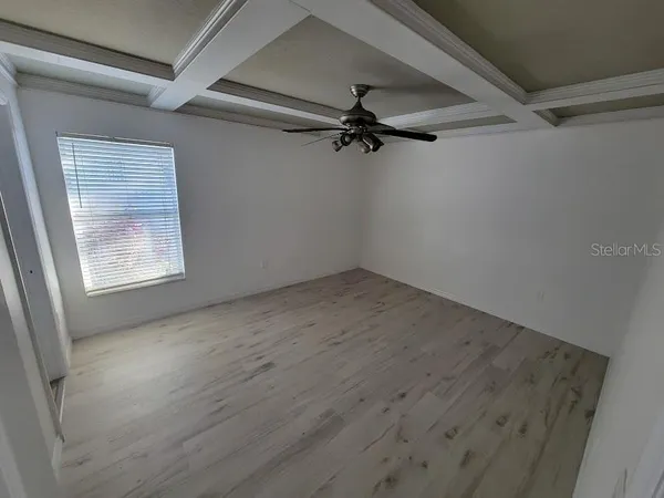 en empty room with wooden floor fan and windows