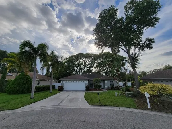 a front view of a house with garden and trees