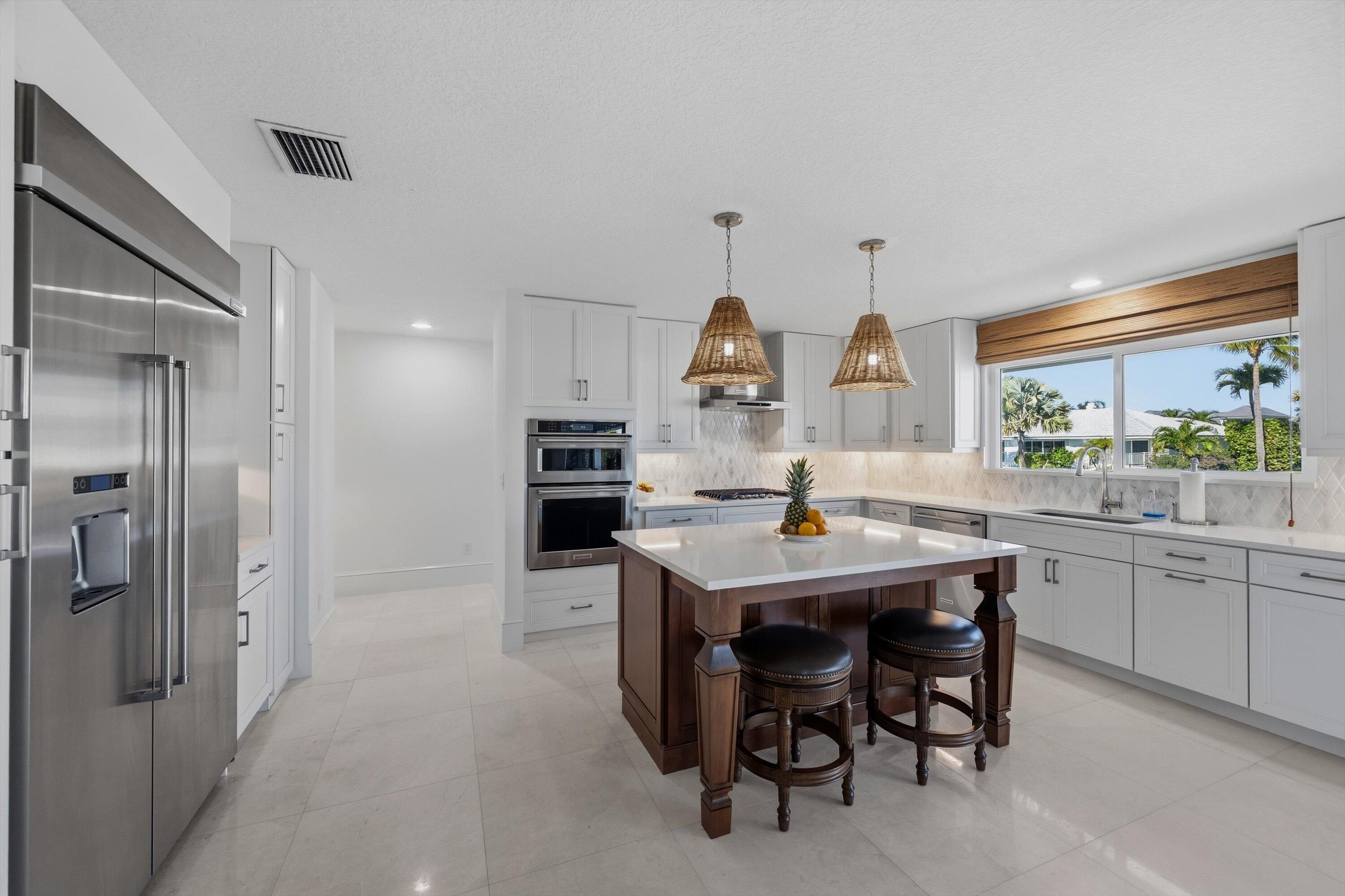 9039 Southeast Hawksbill Way Hobe Sound, FL 33455 - Photo 17 of 45 a kitchen with kitchen island a table and chairs in it