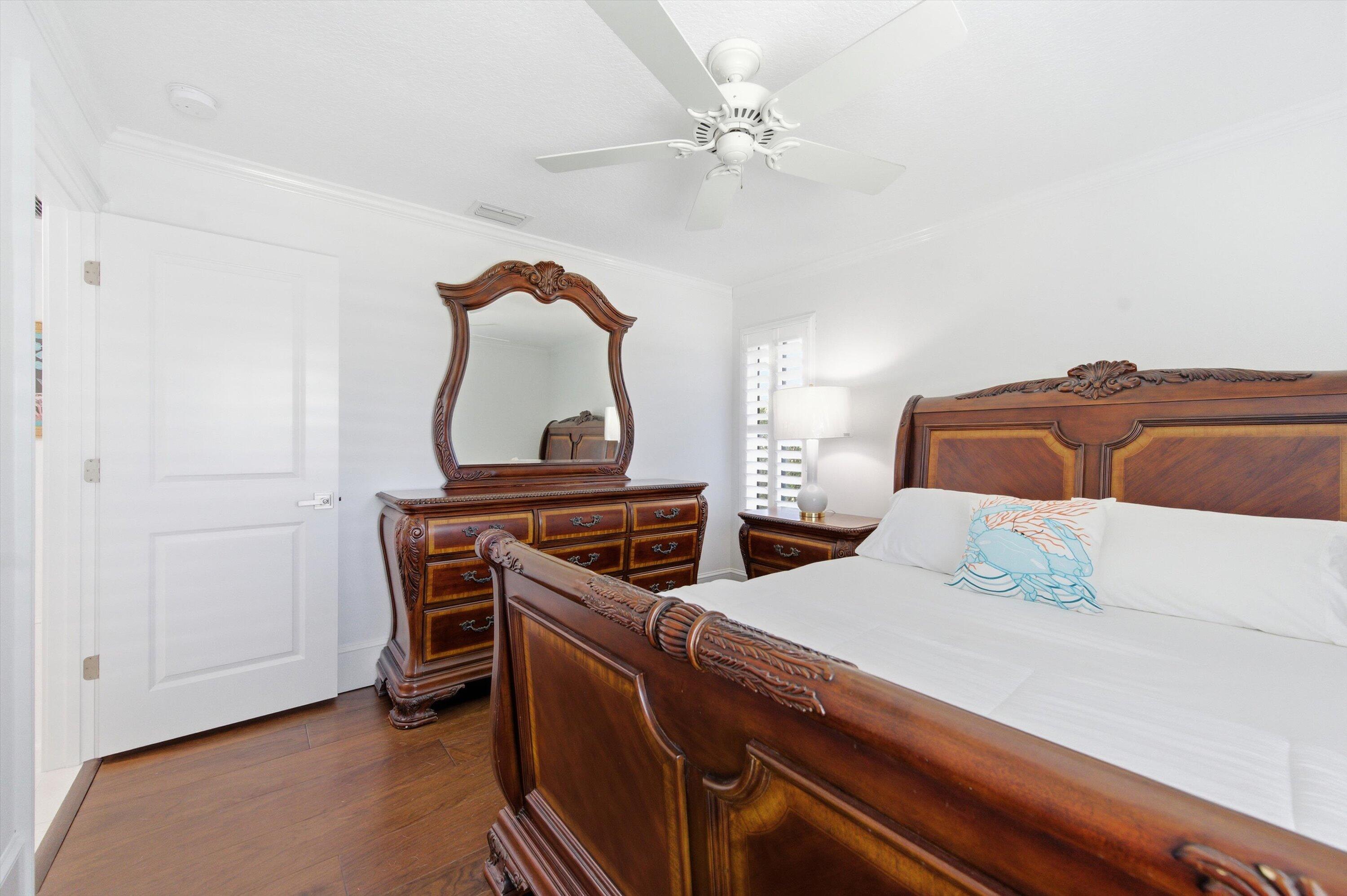 9039 Southeast Hawksbill Way Hobe Sound, FL 33455 - Photo 27 of 45 a bedroom with a bed and a chandelier