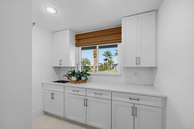 a kitchen with white cabinets and window